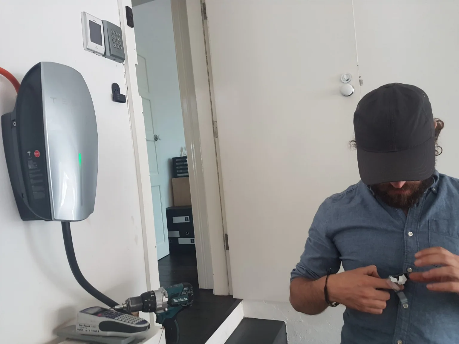Electrician working beside an installed Tesla Wall Connector